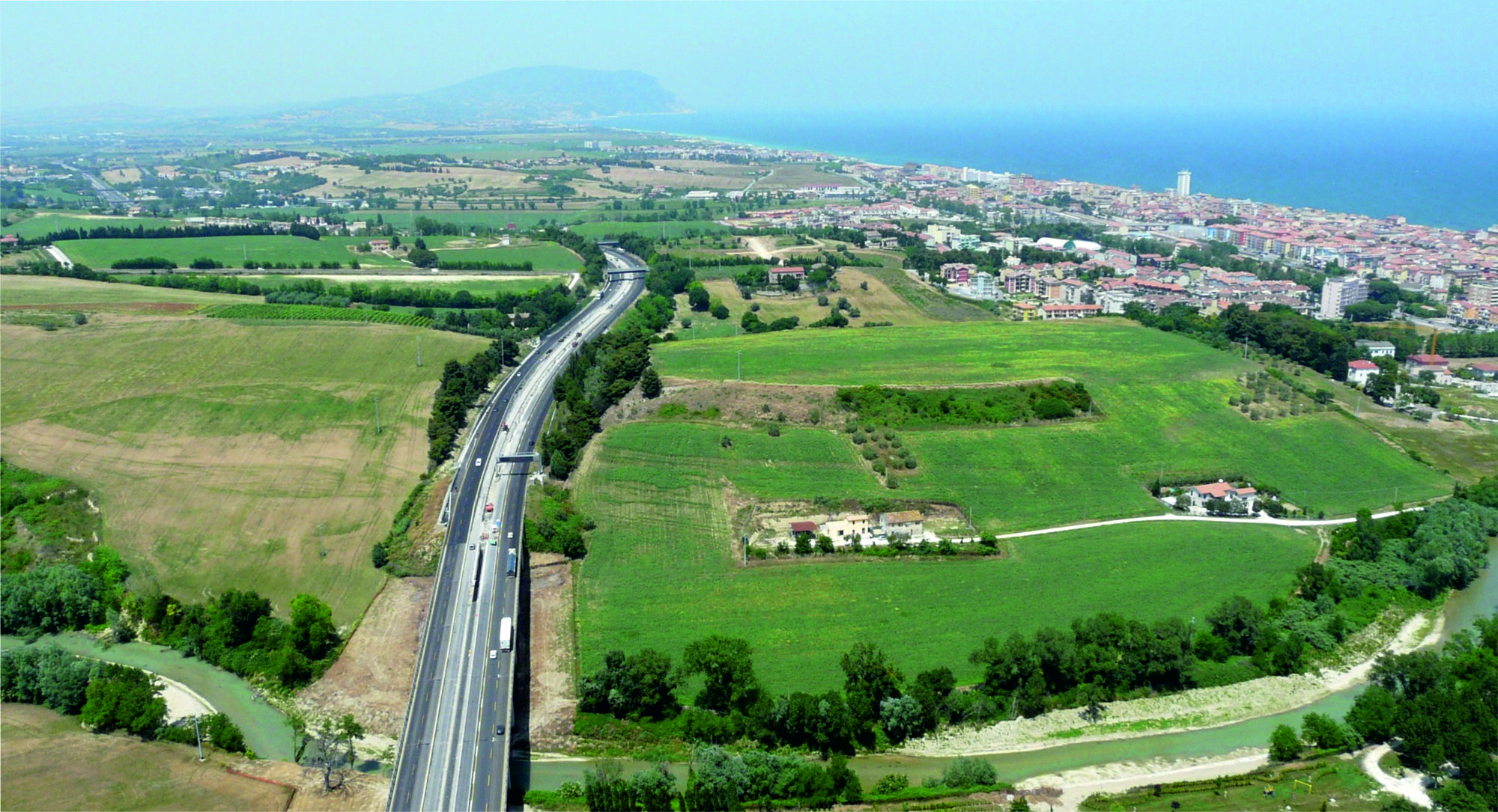 Figure 1 - The archaeological area of Montarice seen from the south, photographed from a small aircraft. The
motorway separates Montarice (right) from the ridge of Colle Burchio (left). River Potenza is visible at the base of
the hill, the town of Porto Recanati in the right. In the far distance is the Conero limestone massif, looking out over
the Adriatic Sea (photograph Frank Vermeulen).